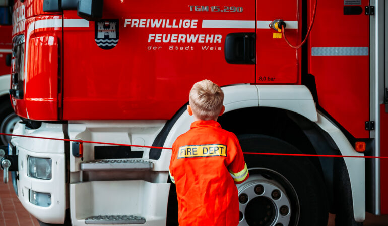 Kind vor Feuerwehrfahrzeug in Fahrzeughalle